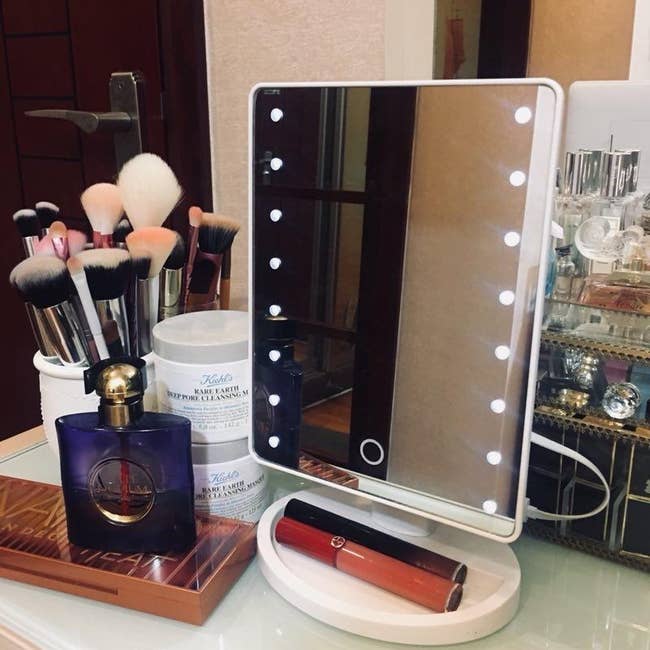 reviewer image of the mirror on a vanity table covered in beauty products