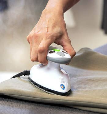 hand using the mini steam iron to iron clothes