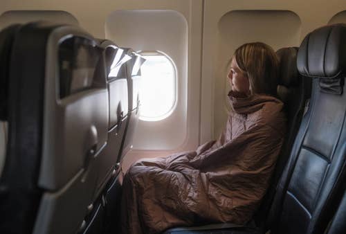 a model on a plane with the blanket fulling covering their body