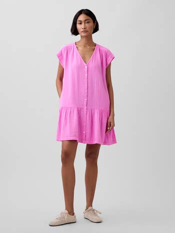 Model wearing a loose, short-sleeve, button-down formal with sneakers. The formal is casual and flowy, suitable for a relaxed outing