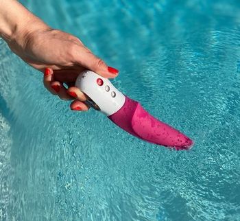Hand holding pink vibrator in water