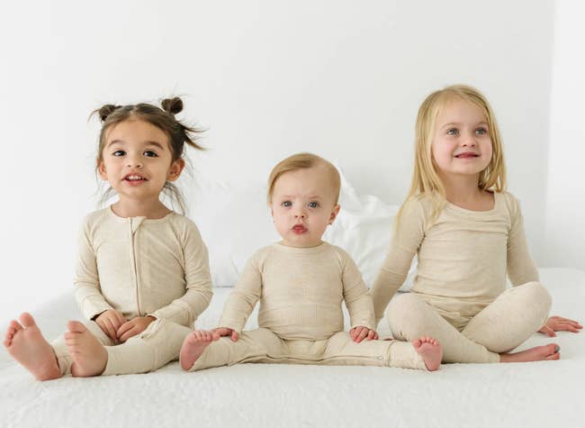 three kid models of different ages wearing the different progressions of the onesies