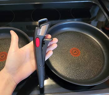 A reviewer holding the removable handle of a sauce pan 