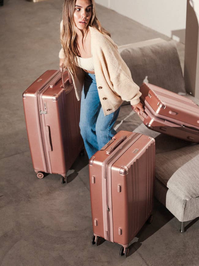 Person successful a casual cardigan and jeans arranging 3 stylish suitcases, perfect for question buying inspiration