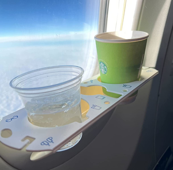 reviewer photo of the bevledge holding two cups while attached to a plane window
