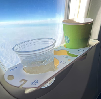 reviewer photo of the bevledge holding two cups while attached to a plane window