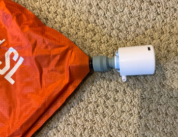 a reviewer photo of a small air pump inserted into the nozzle of an air mattress 