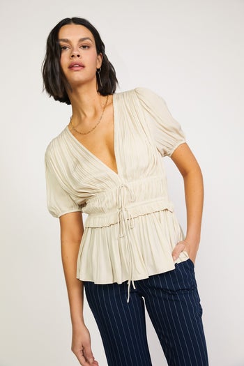 front view of a model wearing the pleated beige top