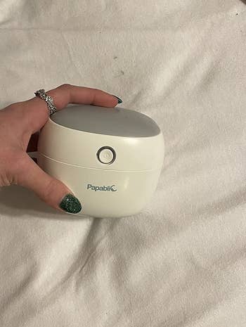 reviewer hand holding the box-shaped sterilizer