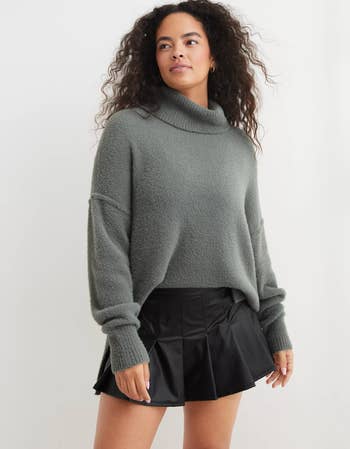a model in a green turtle neck sweater