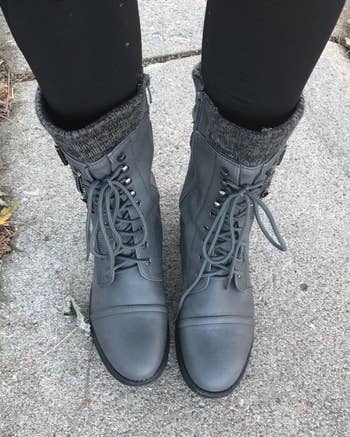 a reviewer wearing gray lace-up boots with black leggings tucked in 