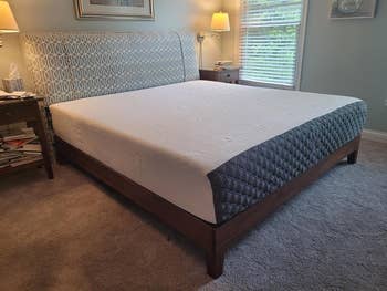 reviewer image of the antique espresso king sized platform bed frame with a mattress atop it