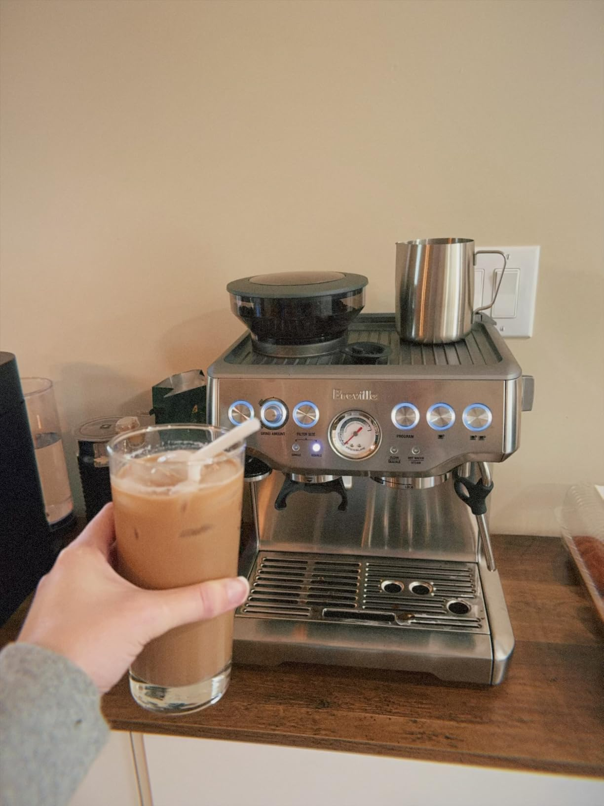 Person holding iced java  adjacent  to a modern   espresso instrumentality   connected  a room  counter