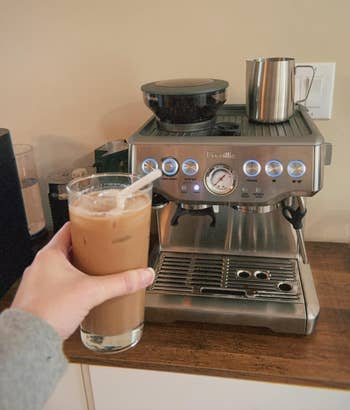 Person holding iced java adjacent to a modern espresso instrumentality connected a room counter