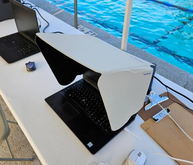 Portable laptop sunshade on a laptop sitting on a desk by a pool