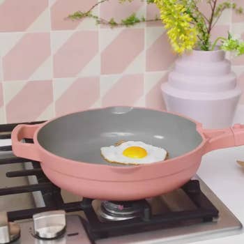 a fried egg inside the pink always pan which sits on a stove