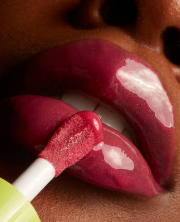 model applying lip oil to lips