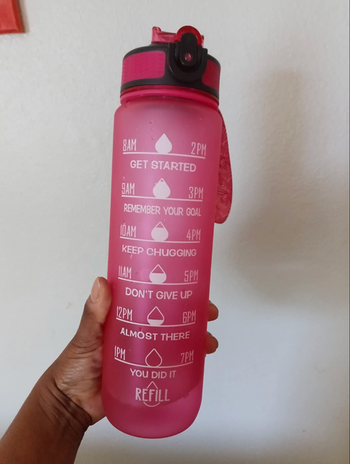 A reviewer holding up a pink time marked water bottle