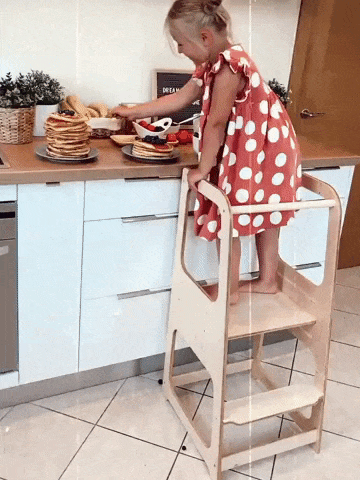Gif of a child standing on the wooden stool and helping in the kitchen