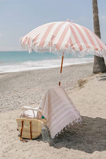 pink and white striped umbrella over a beach chair on the beach