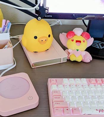 Reviewer's pink mug warmer on their desk next to their keyboard, laptop, and other office supplies
