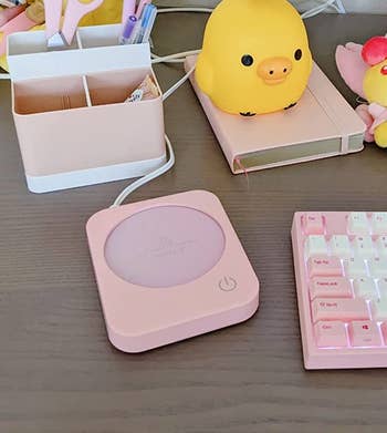 Reviewer's pink mug warmer on their desk next to their keyboard, laptop, and other office supplies