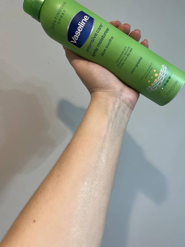 Person applying Vaseline Intensive Care Aloe Soothe spray moisturizer connected forearm