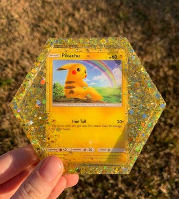 seller holding yellow glittery Pikachu card coaster