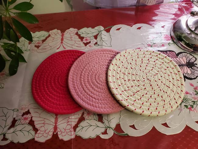 a set of three trivets in red, pink, and speckled designs