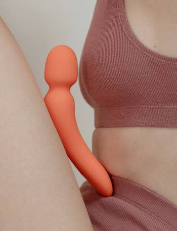 Person successful knit covering holds a modern, sleek, orangish wellness merchandise connected their hip, highlighting its ergonomic design