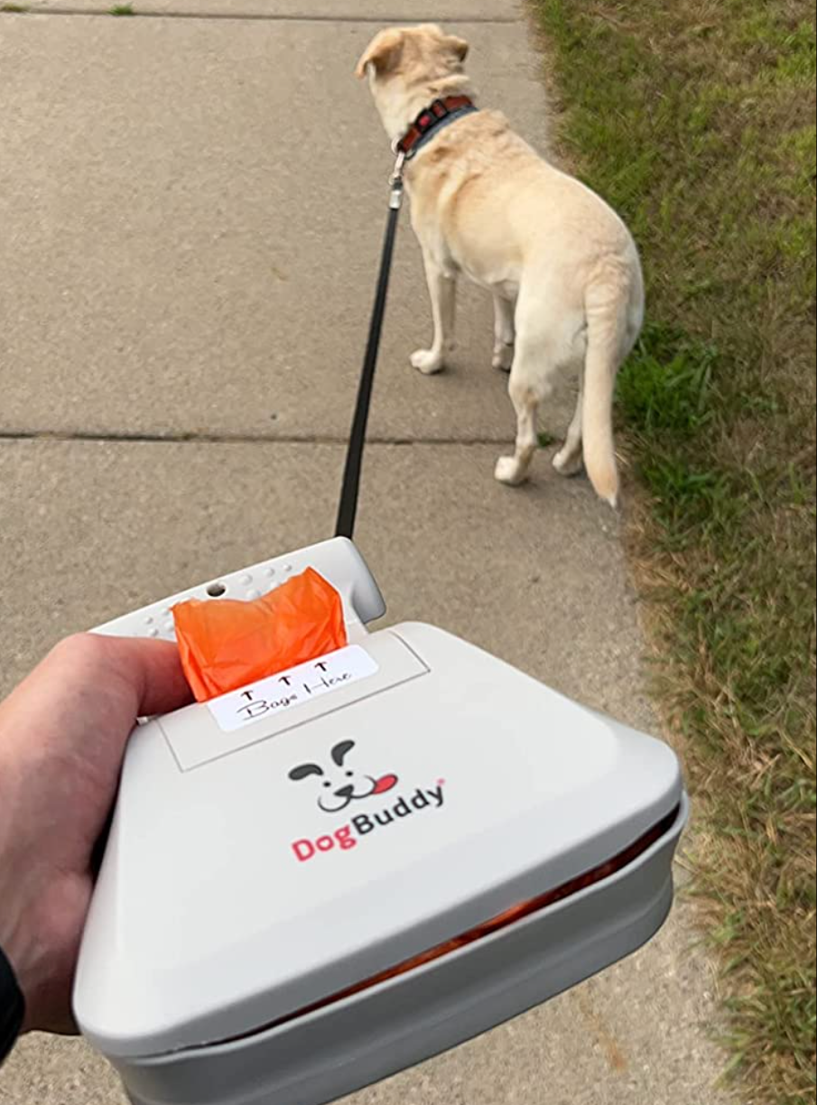 reviewer holding scooping mechanism with built in bags attached to a dog's leash