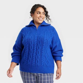 a model wearing a blue cable knit quarter zip sweater