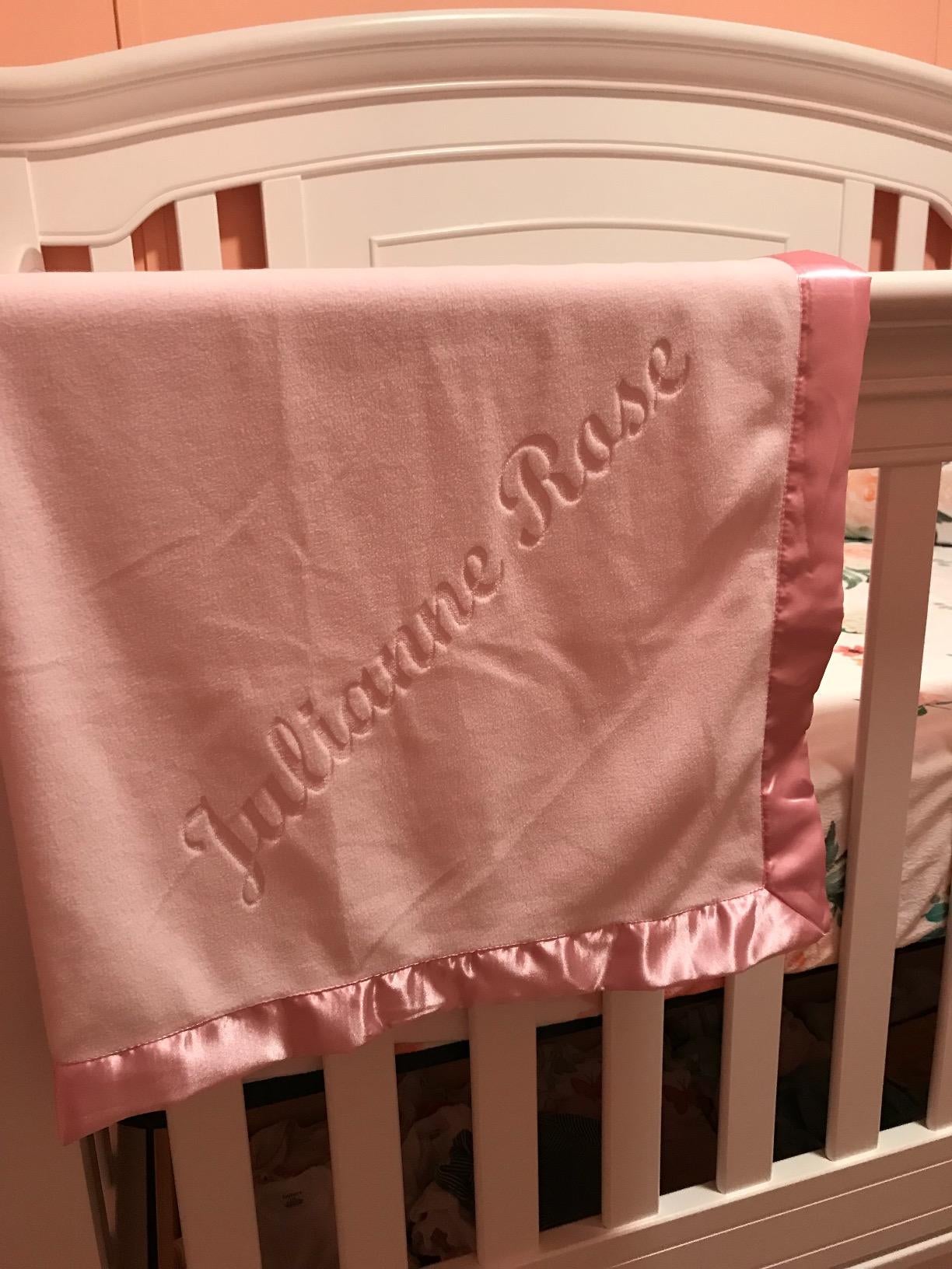 Reviewer image of pink baby blanket with silk edges and the name 