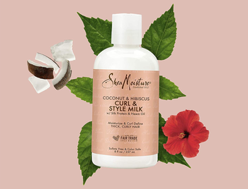 the bottle of styling milk in front of a graphic of leaves, hibiscus, and coconut 
