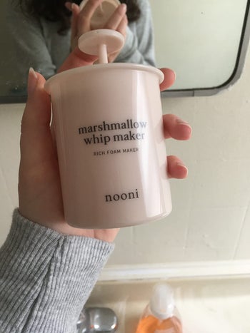 reviewer holding a pink cup-sized device with a pump top