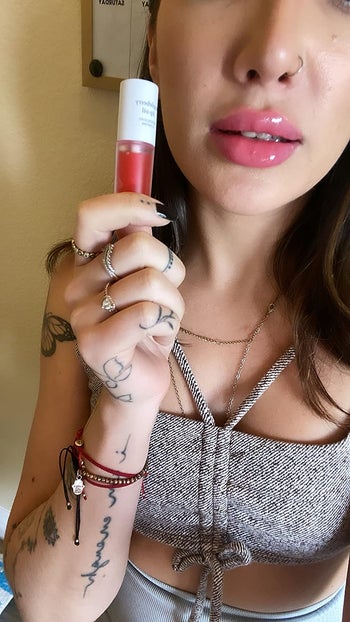 Reviewer holding the appleberry lip oil with it applied on lips