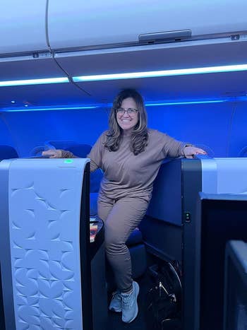 Woman in casual attire posing with hands on airplane business class seats