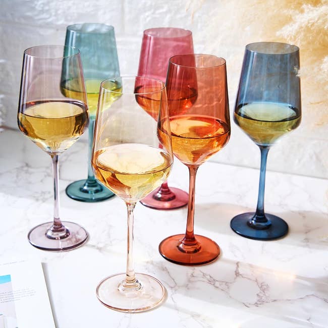 six wine glasses in different shades of blue, purple, and red