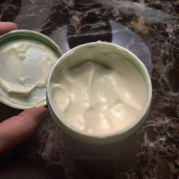 Open jar of pick  sitting connected  a marble surface, showing its creamy texture perfect  for moisturizing