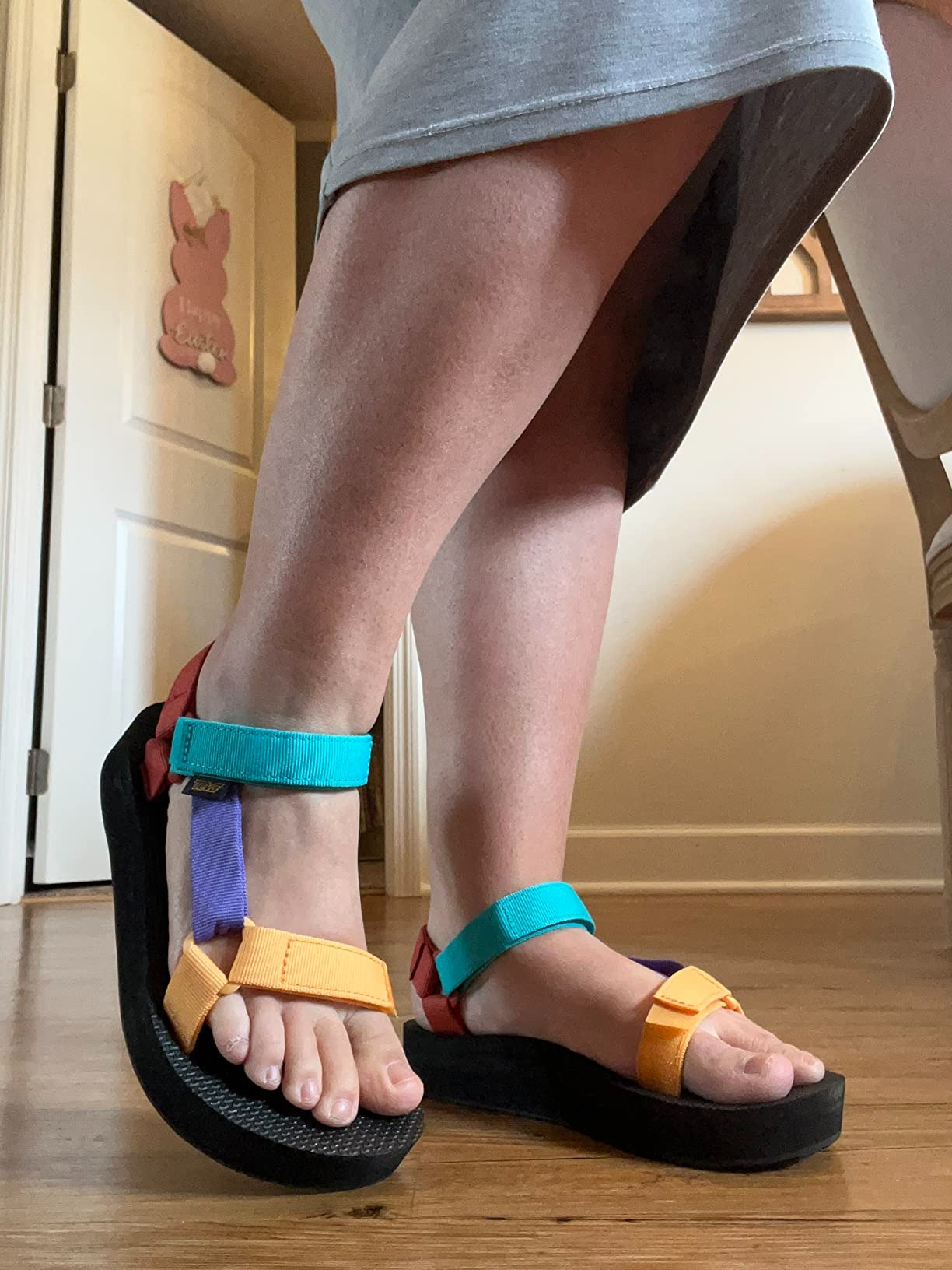 a reviewer wearing a grey  skirt and multicolored teva sandals