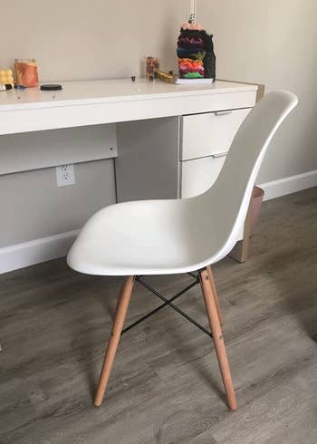 a reviewer photo of the same chair in white in. front of a desk 
