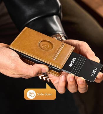 A person holding a leather cardholder with cards sliding out. Text: