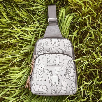 a grey sling backpack with a winnie the pooh print on it