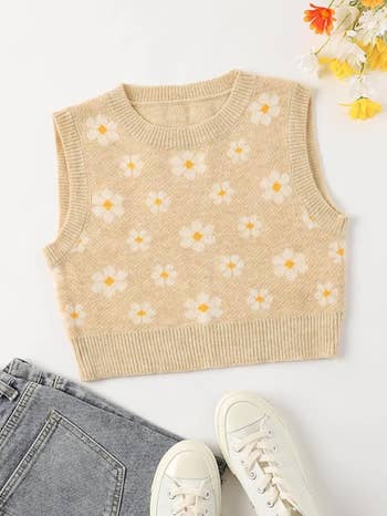 Knit vest with flower pattern paired with gray jeans and white sneakers, flat lay for shopping article