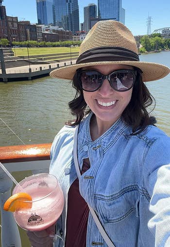 another reviewer wearing the straw fedora on a river boat