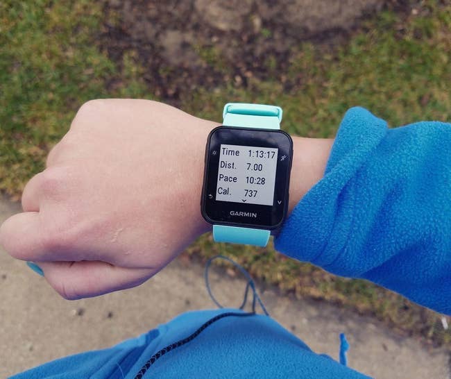 reviewer wears Garmin GPS Running Watch with screen that reads running time, distance, pace, and calories burned and a blue strap