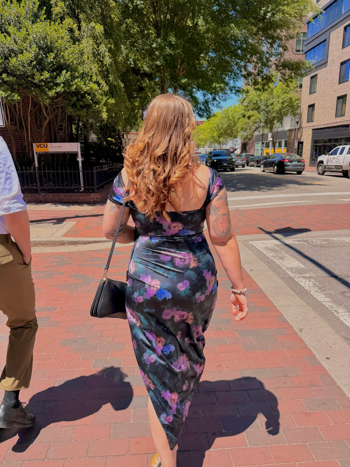 Person walking connected  a ceramic  sidewalk wearing a floral dress, holding a bag