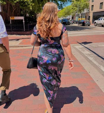 Person walking connected a ceramic sidewalk wearing a floral dress, holding a bag