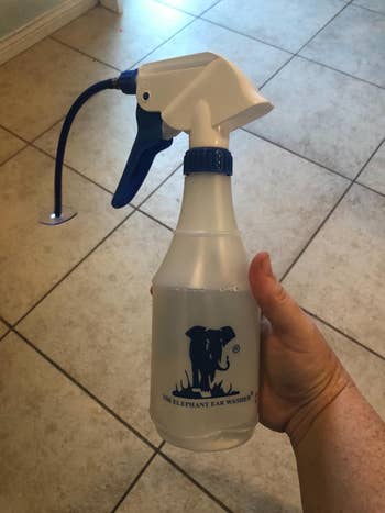 A hand holding an Elephant Ear Washer spray bottle, used for ear cleaning