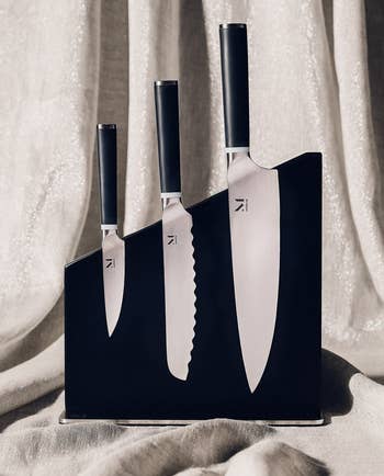 three knives with black handles stored upright in a black block